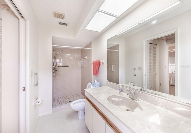 bathroom featuring toilet, a skylight, a tile shower, vanity, and tile patterned flooring