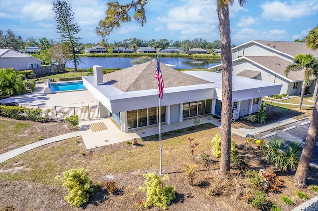 rear view of property featuring a fenced in pool and a water view