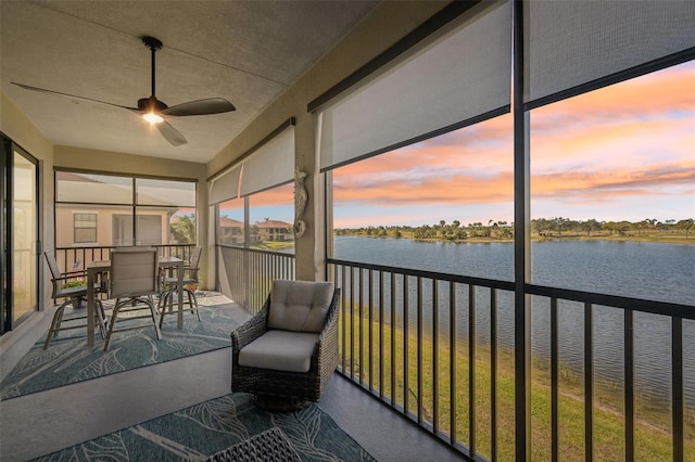 unfurnished sunroom featuring a water view and ceiling fan