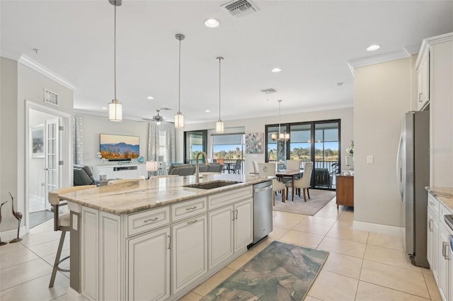 kitchen with sink, hanging light fixtures, an island with sink, stainless steel appliances, and light stone countertops