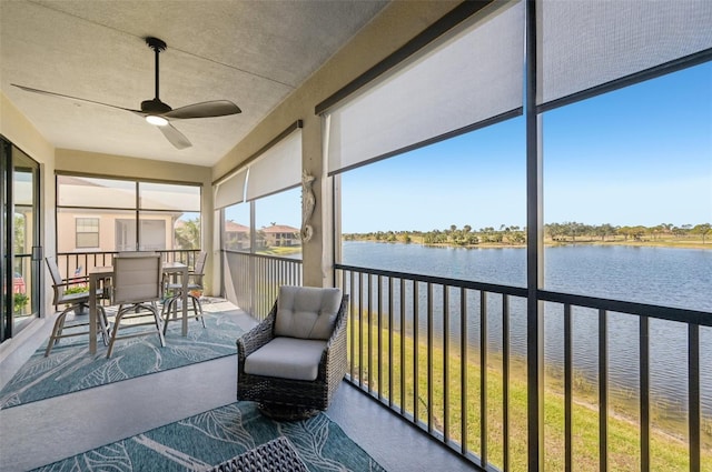 unfurnished sunroom featuring ceiling fan and a water view