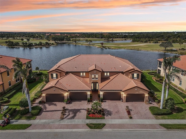 aerial view at dusk featuring a water view