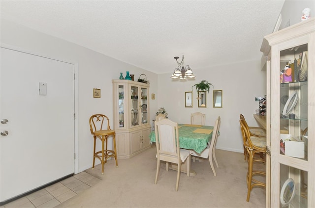 dining area with light colored carpet, a textured ceiling, and a notable chandelier