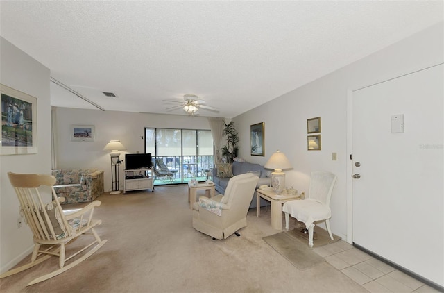 living room with ceiling fan, light colored carpet, and a textured ceiling