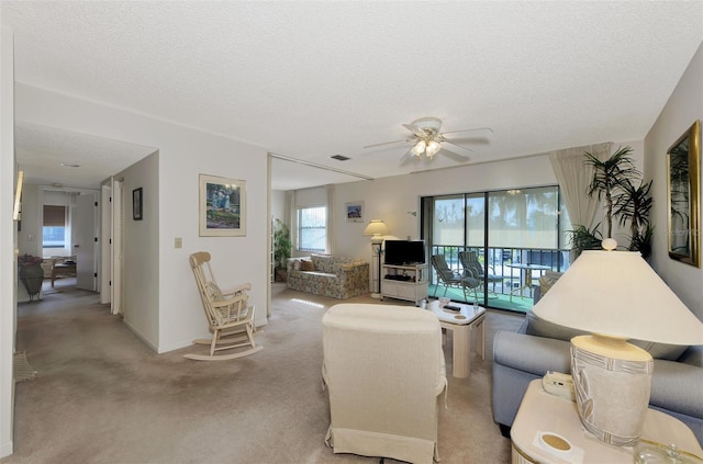 living room with ceiling fan, light colored carpet, and a textured ceiling