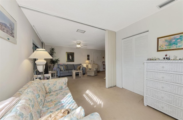 carpeted living room featuring ceiling fan and a textured ceiling