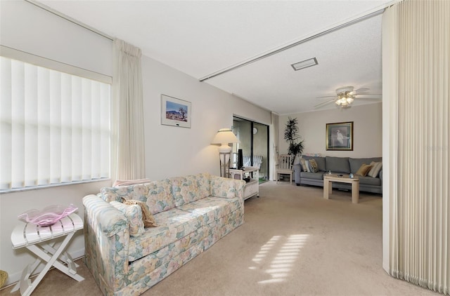 living room featuring ceiling fan, a textured ceiling, light carpet, and a wealth of natural light