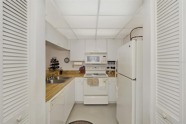 kitchen featuring white cabinetry, white appliances, sink, and a drop ceiling