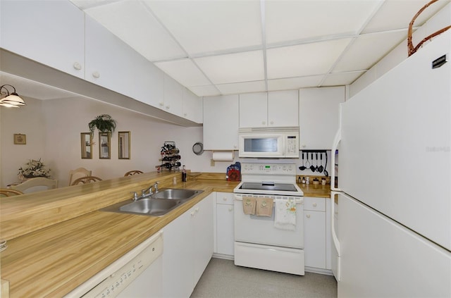 kitchen featuring butcher block countertops, sink, white cabinets, a drop ceiling, and white appliances