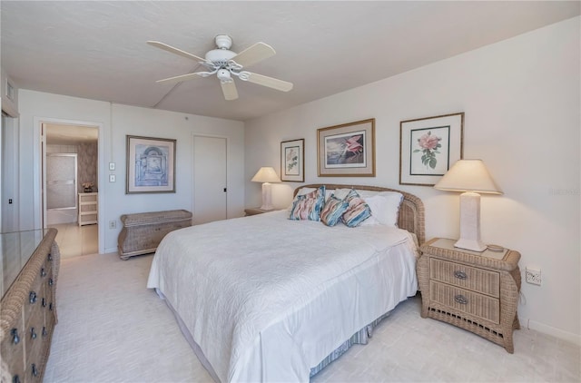 carpeted bedroom with ensuite bathroom and ceiling fan