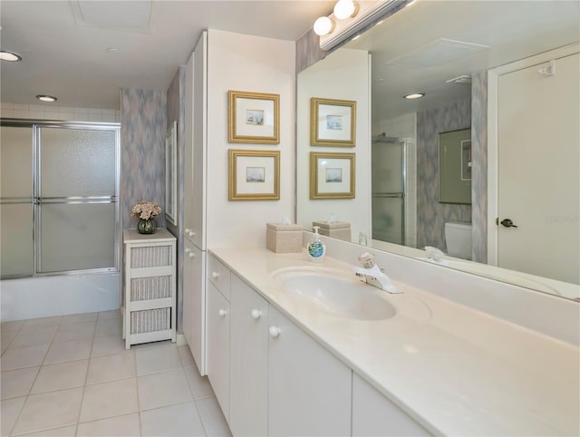 full bathroom with tile patterned flooring, vanity, bath / shower combo with glass door, and toilet