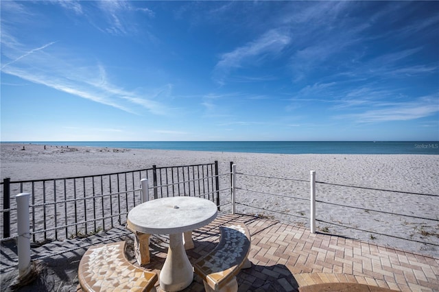 view of patio featuring a balcony, a water view, and a beach view