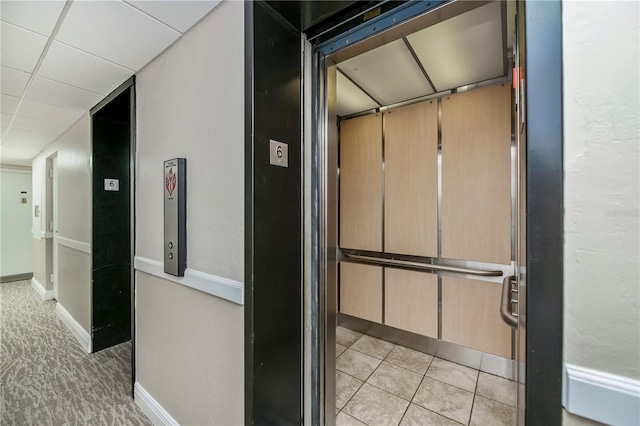 hall featuring elevator, a paneled ceiling, and light tile patterned floors