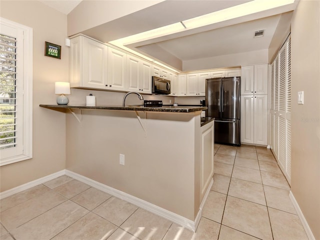 kitchen featuring white cabinetry, light tile patterned floors, stainless steel refrigerator, and kitchen peninsula