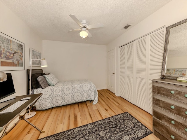 bedroom featuring ceiling fan, wood-type flooring, a closet, and a textured ceiling