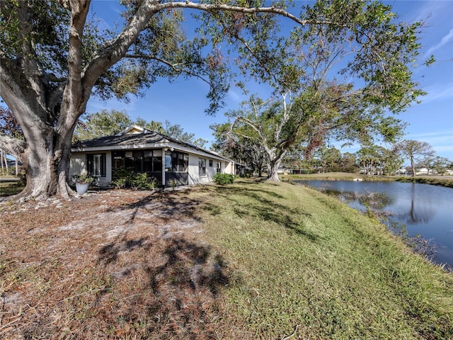 view of yard featuring a water view and a sunroom