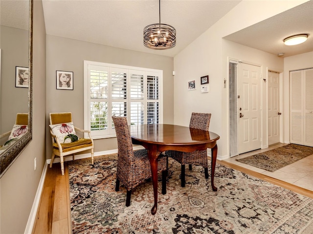 dining area with a textured ceiling, light hardwood / wood-style flooring, and a chandelier