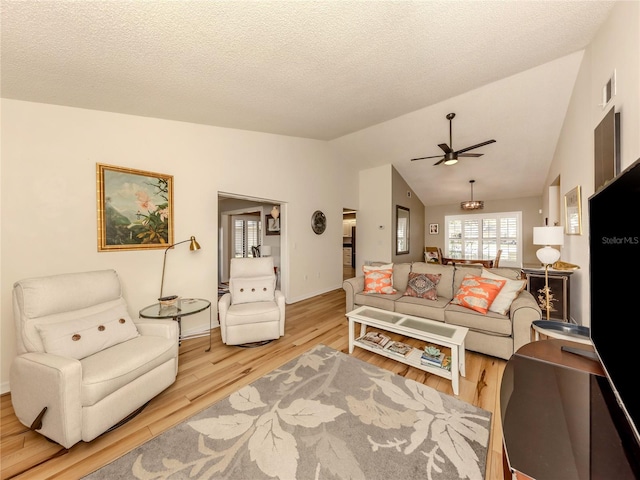 living room featuring lofted ceiling, light hardwood / wood-style floors, and a textured ceiling