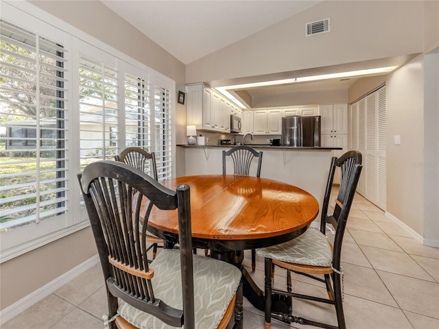 tiled dining area with lofted ceiling and a wealth of natural light