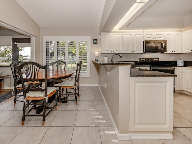 kitchen featuring vaulted ceiling, dark stone countertops, electric range, kitchen peninsula, and white cabinets