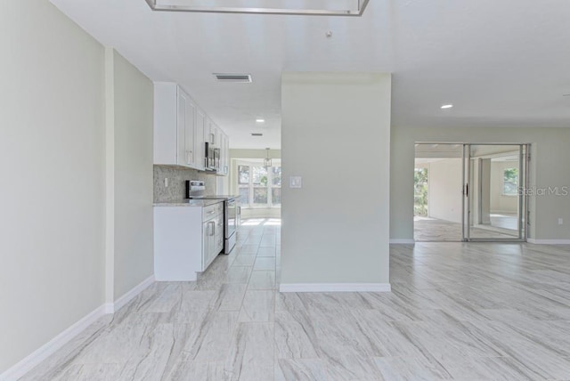 kitchen featuring white cabinetry, tasteful backsplash, appliances with stainless steel finishes, and light stone counters