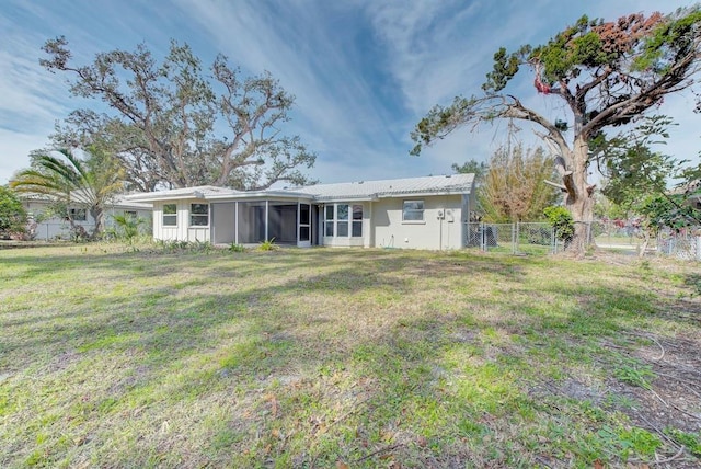 rear view of property with a sunroom and a lawn