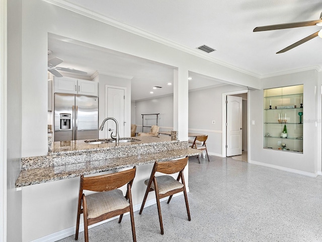 kitchen featuring sink, white cabinetry, light stone counters, stainless steel fridge, and ceiling fan