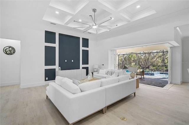 living room featuring beam ceiling, coffered ceiling, a towering ceiling, and light wood-type flooring