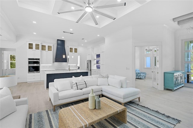 living room with a healthy amount of sunlight, beam ceiling, and light hardwood / wood-style flooring