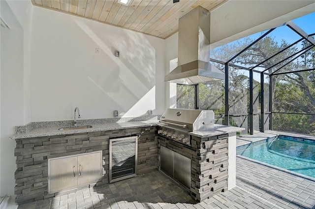 view of patio / terrace with an outdoor kitchen, area for grilling, sink, beverage cooler, and glass enclosure