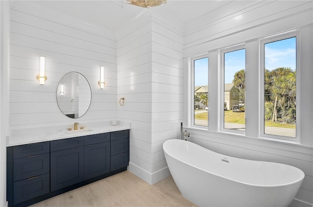 bathroom featuring vanity, a tub to relax in, hardwood / wood-style floors, and a healthy amount of sunlight