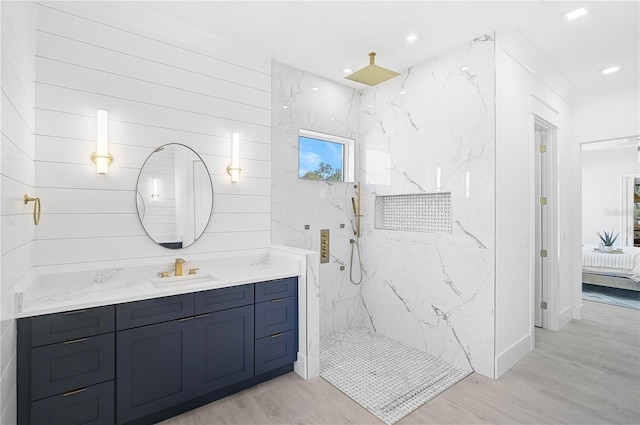 bathroom featuring hardwood / wood-style flooring, tiled shower, and vanity