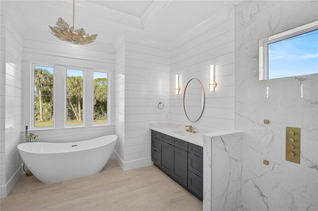 bathroom featuring vanity, a tub to relax in, a wealth of natural light, and wood-type flooring