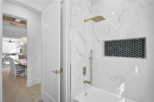 bathroom with hardwood / wood-style flooring and tiled shower / bath