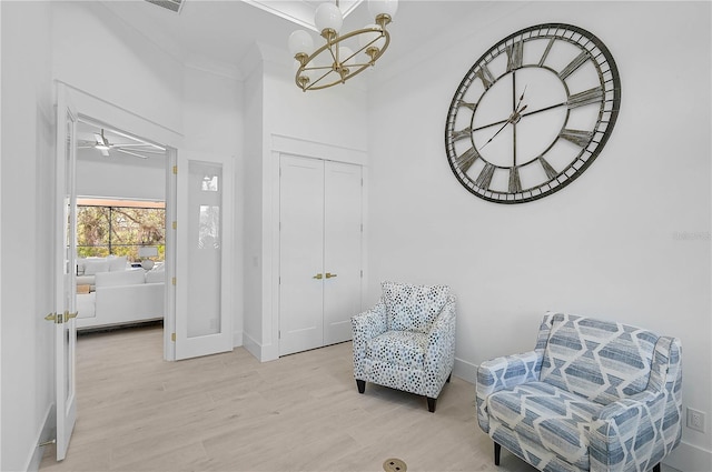 sitting room with crown molding, a chandelier, and light hardwood / wood-style floors