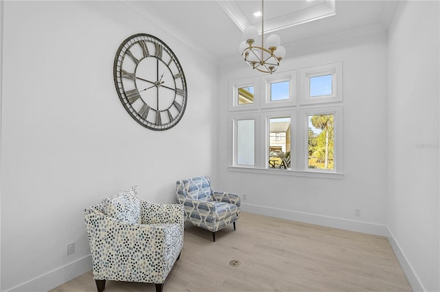 living area with ornamental molding, a raised ceiling, and light wood-type flooring