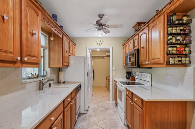 kitchen featuring sink, ceiling fan, appliances with stainless steel finishes, light stone countertops, and decorative backsplash