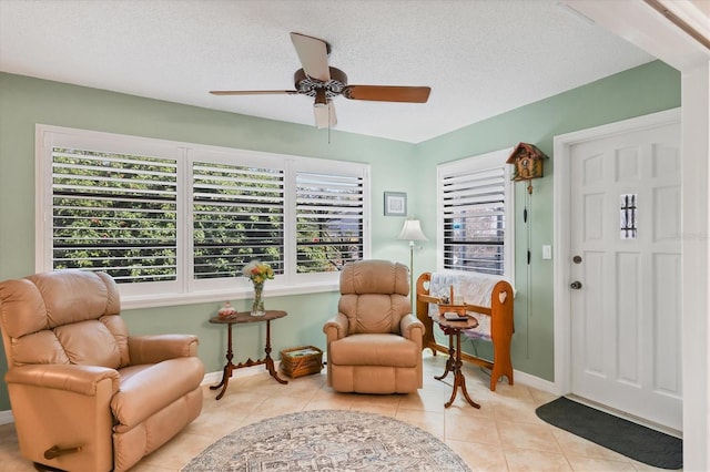 sitting room featuring ceiling fan, light tile patterned floors, and a textured ceiling