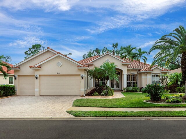 mediterranean / spanish-style house with a garage and a front lawn