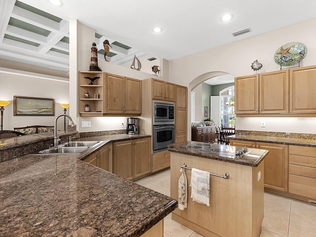 kitchen with sink, light tile patterned floors, appliances with stainless steel finishes, coffered ceiling, and a kitchen island