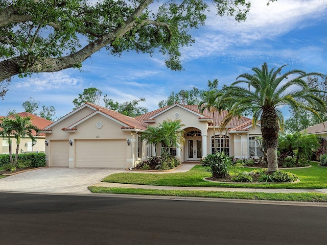 mediterranean / spanish home featuring a garage and a front yard