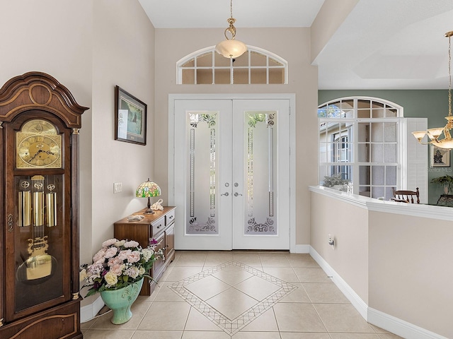 entryway with light tile patterned flooring, an inviting chandelier, and french doors