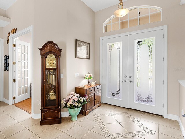 entryway with a towering ceiling, light tile patterned floors, and french doors