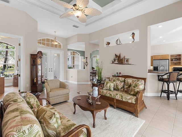 living room with french doors, ceiling fan, a raised ceiling, and light tile patterned floors