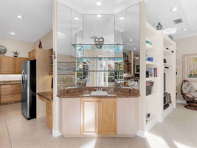 kitchen with light brown cabinetry, sink, light tile patterned floors, stainless steel fridge, and dark stone counters