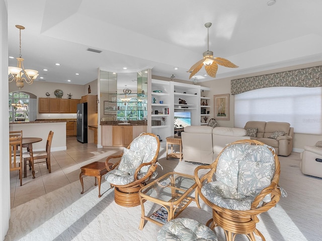 living room featuring crown molding, a raised ceiling, ceiling fan with notable chandelier, and light tile patterned floors