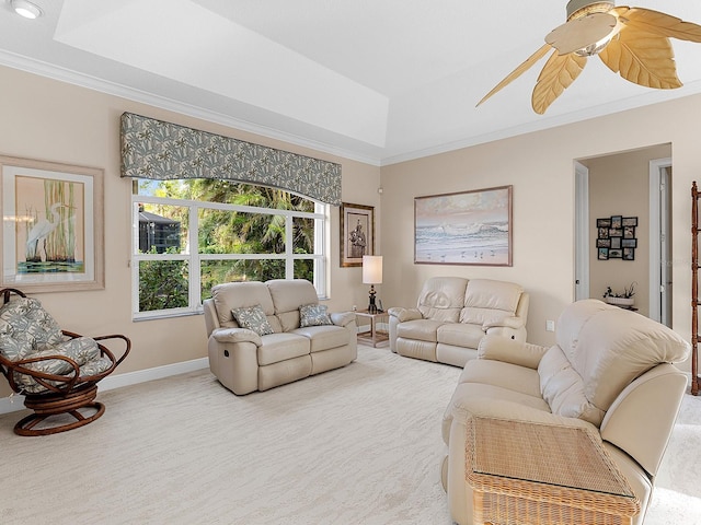 carpeted living room with ornamental molding, a raised ceiling, and ceiling fan