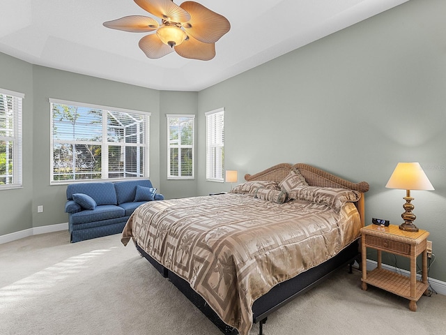 bedroom with a raised ceiling, ceiling fan, and carpet flooring