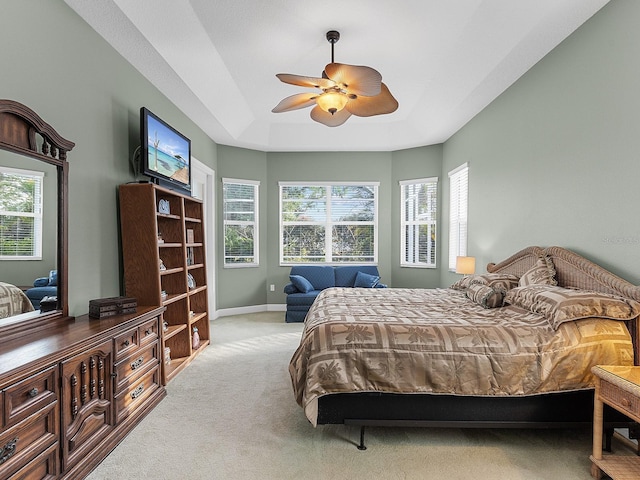 carpeted bedroom featuring ceiling fan and a tray ceiling