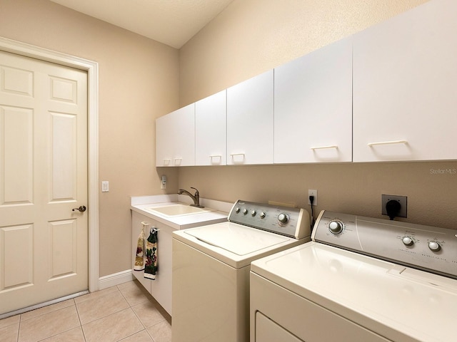 laundry room with cabinets, light tile patterned flooring, washer and dryer, and sink